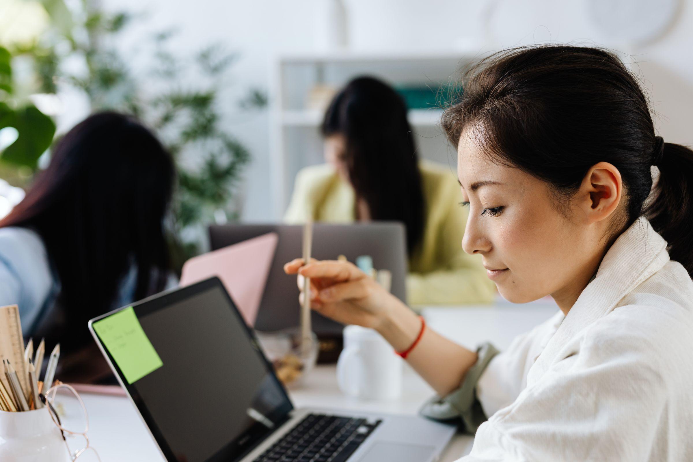 An in-house IT team member working at a laptop with colleagues behind her