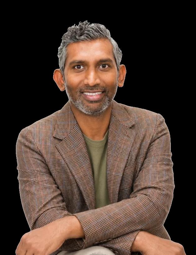 Chath Weerasinghe, Group Head of Finance and IT at MUJI Europe Holdings Limited, seated with his arms crossed and smiling