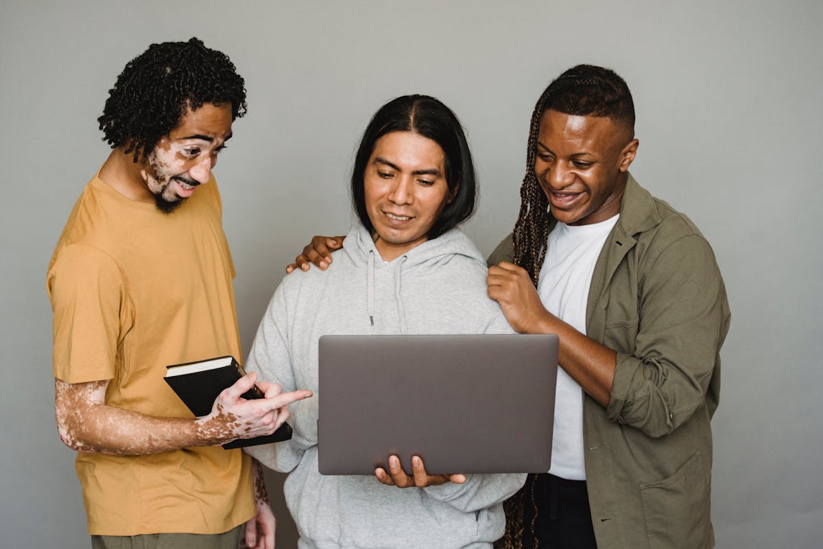 Three colleagues reviewing work on a laptop away from a desk